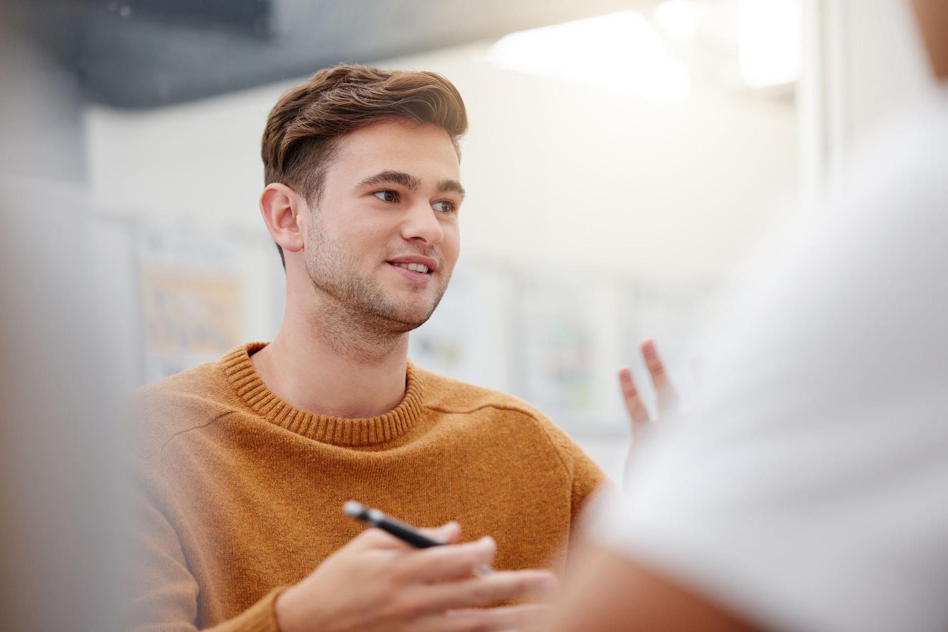 A student engages in conversation with another man in an office setting, exchanging ideas and insights.