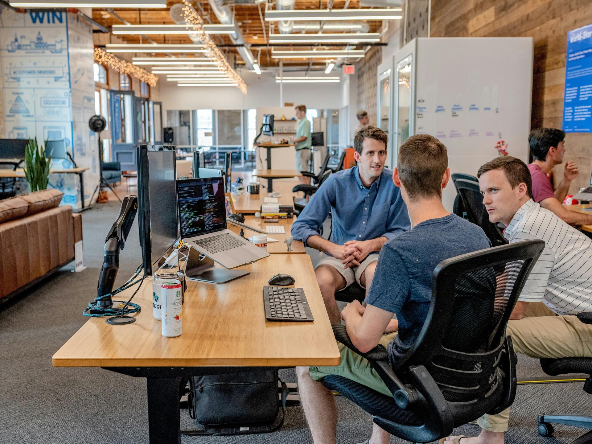 People collaborating in a modern open-plan office with computers.