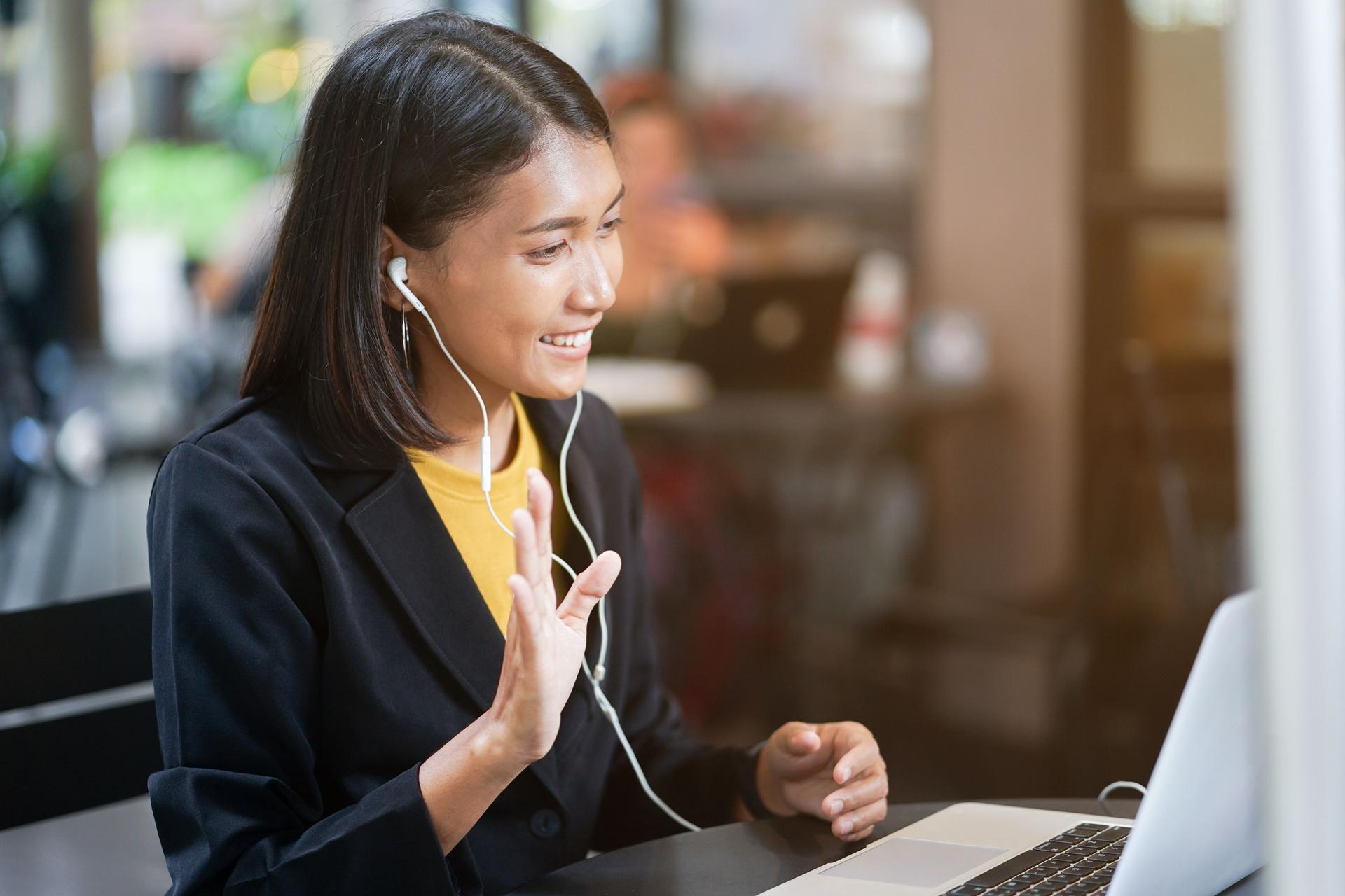 A business-suited woman engages with her laptop for a graduate school interview.