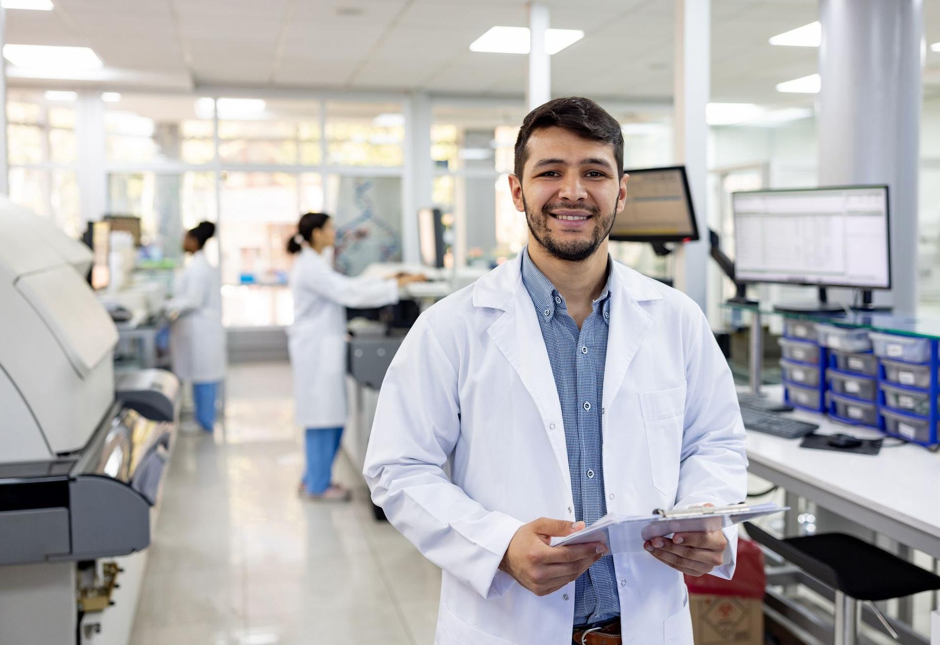  A man in a lab coat stands confidently in a well-equipped laboratory, surrounded by scientific instruments and equipment.