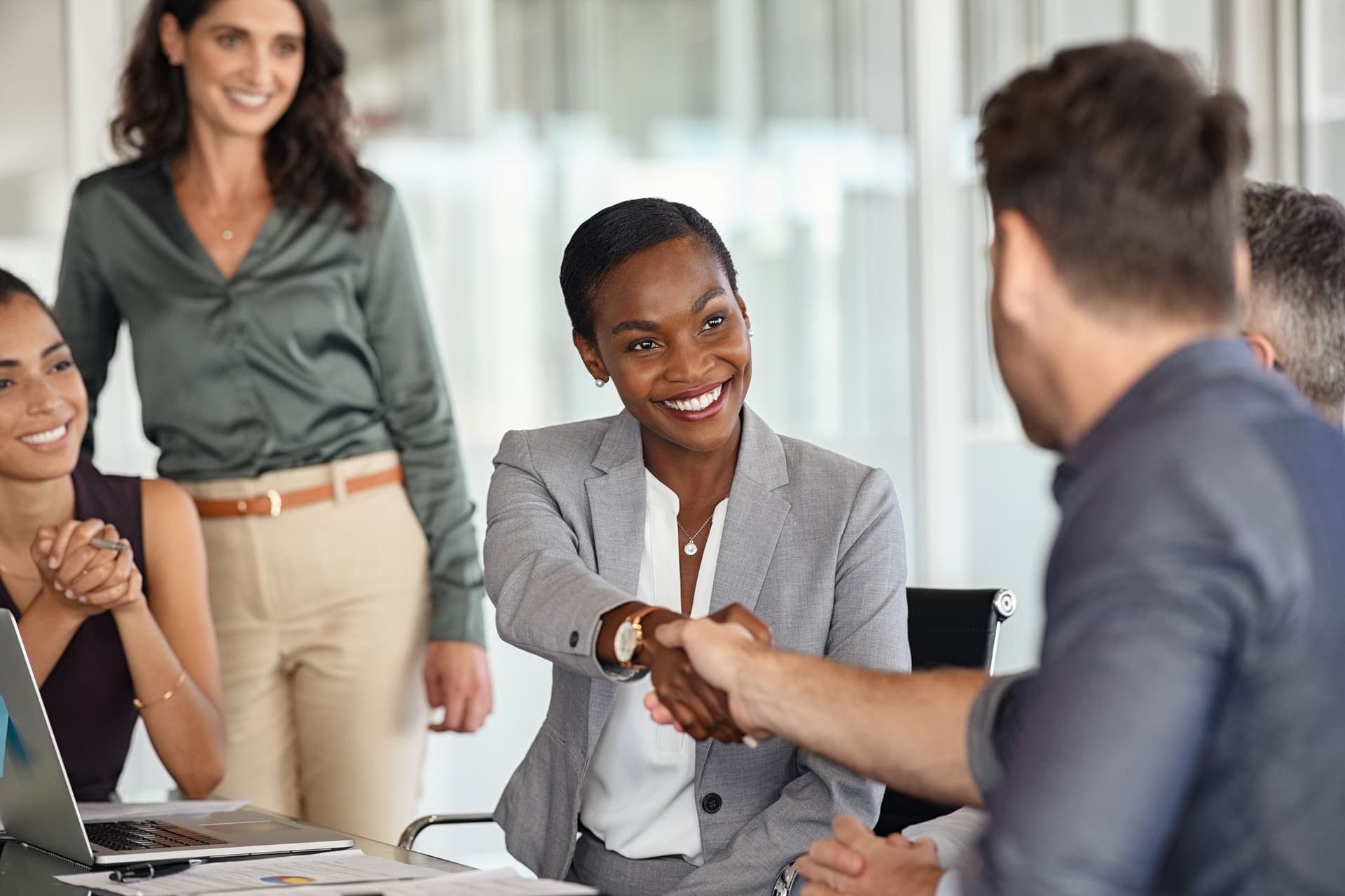 A diverse group of professionals shaking hands during a meeting, symbolizing collaboration and agreement.