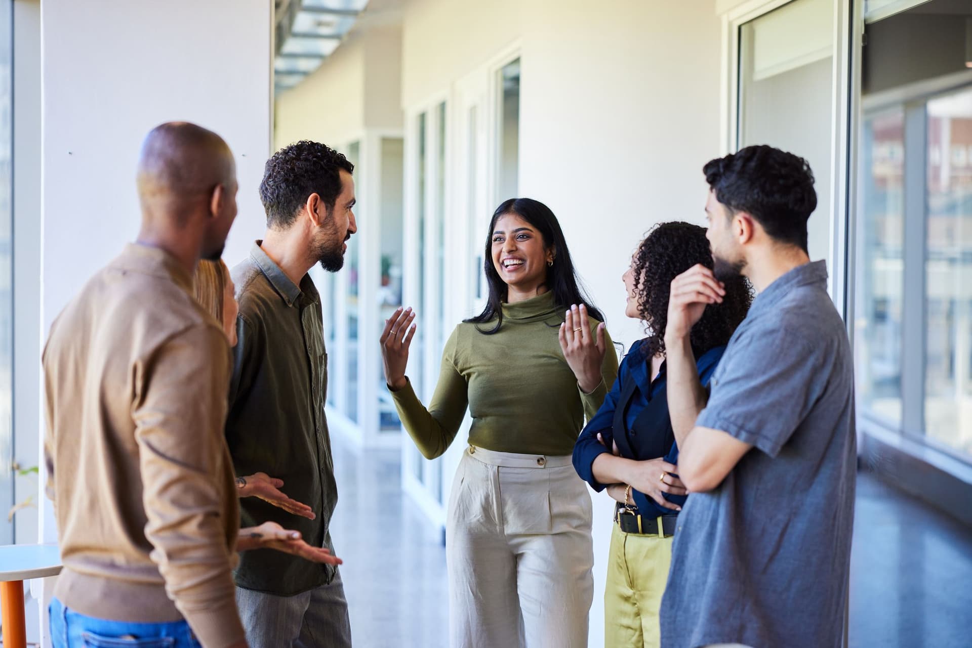 A group of diverse individuals engaged in conversation in a modern office setting.