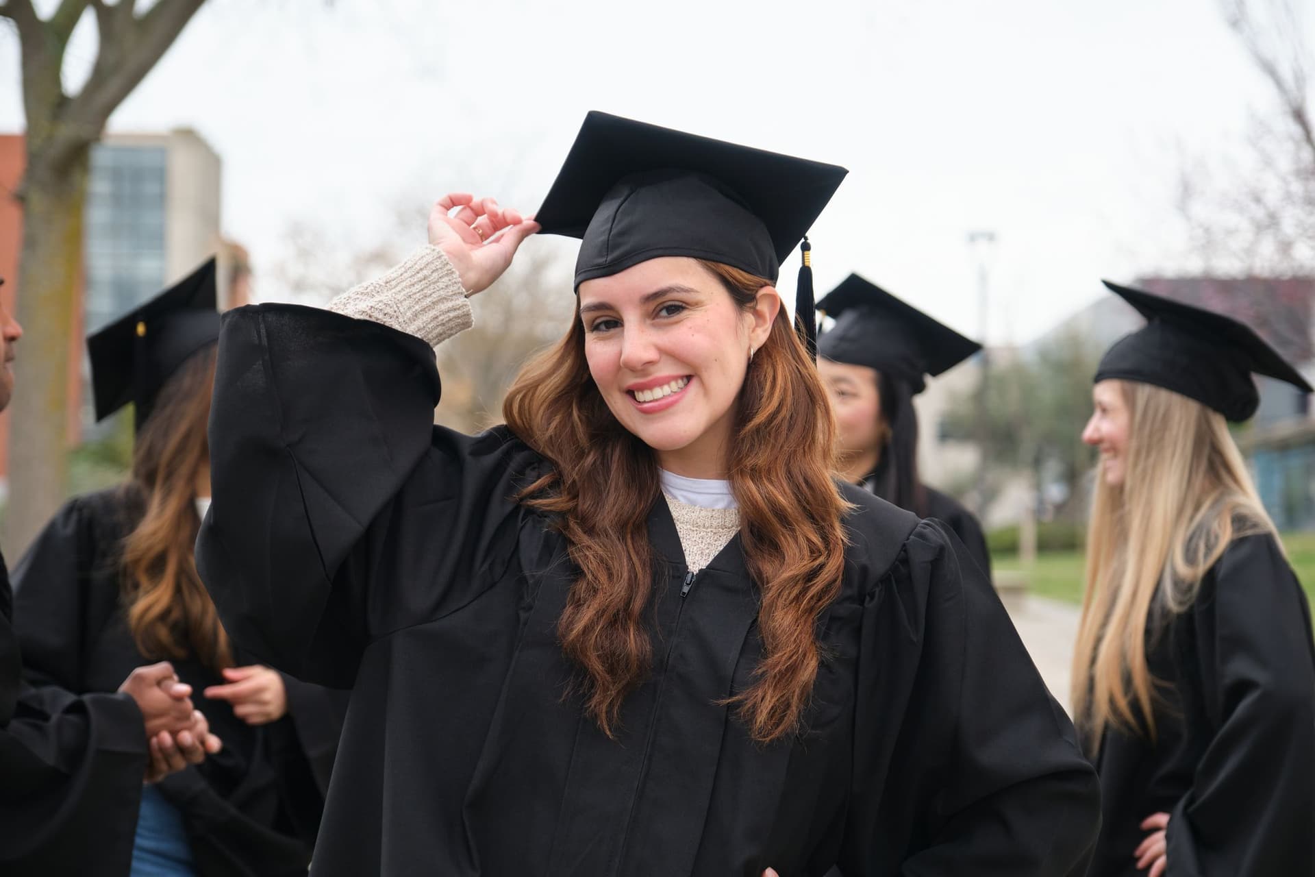 A woman in a graduation gown smiles happily, marking her graduation day. 