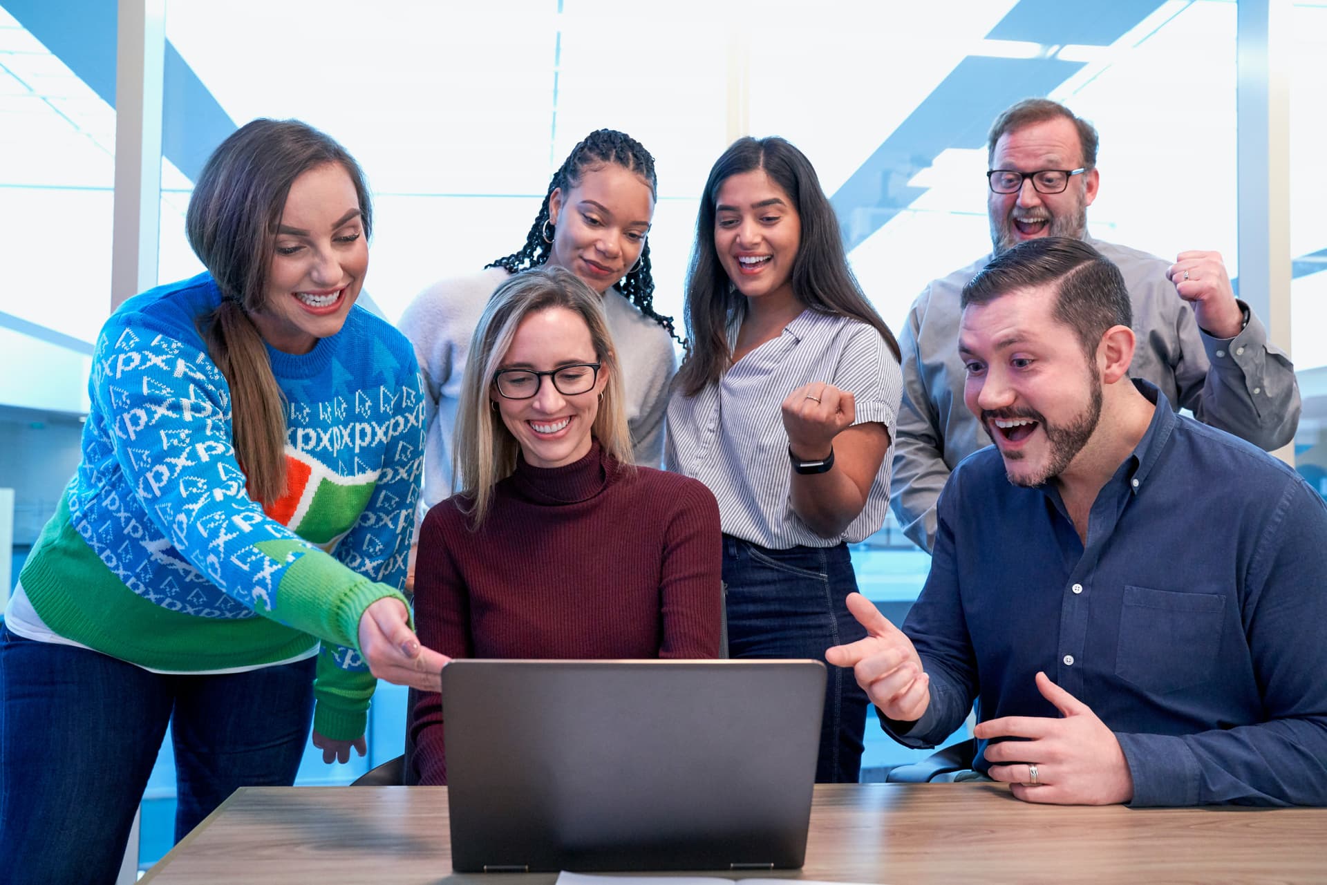 Group of people excitedly looking at a laptop.