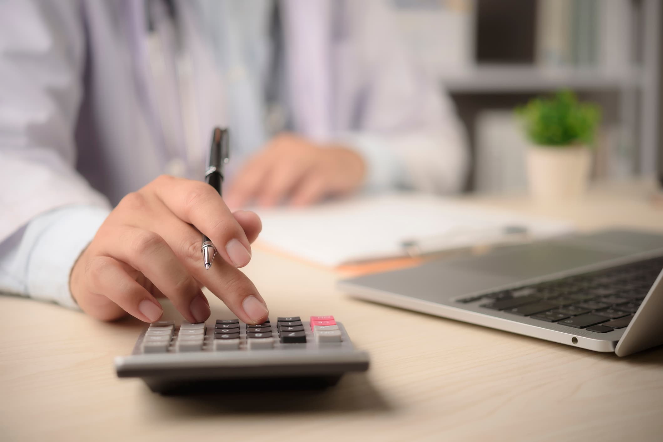 A person uses a calculator to determine the cost in an office environment.