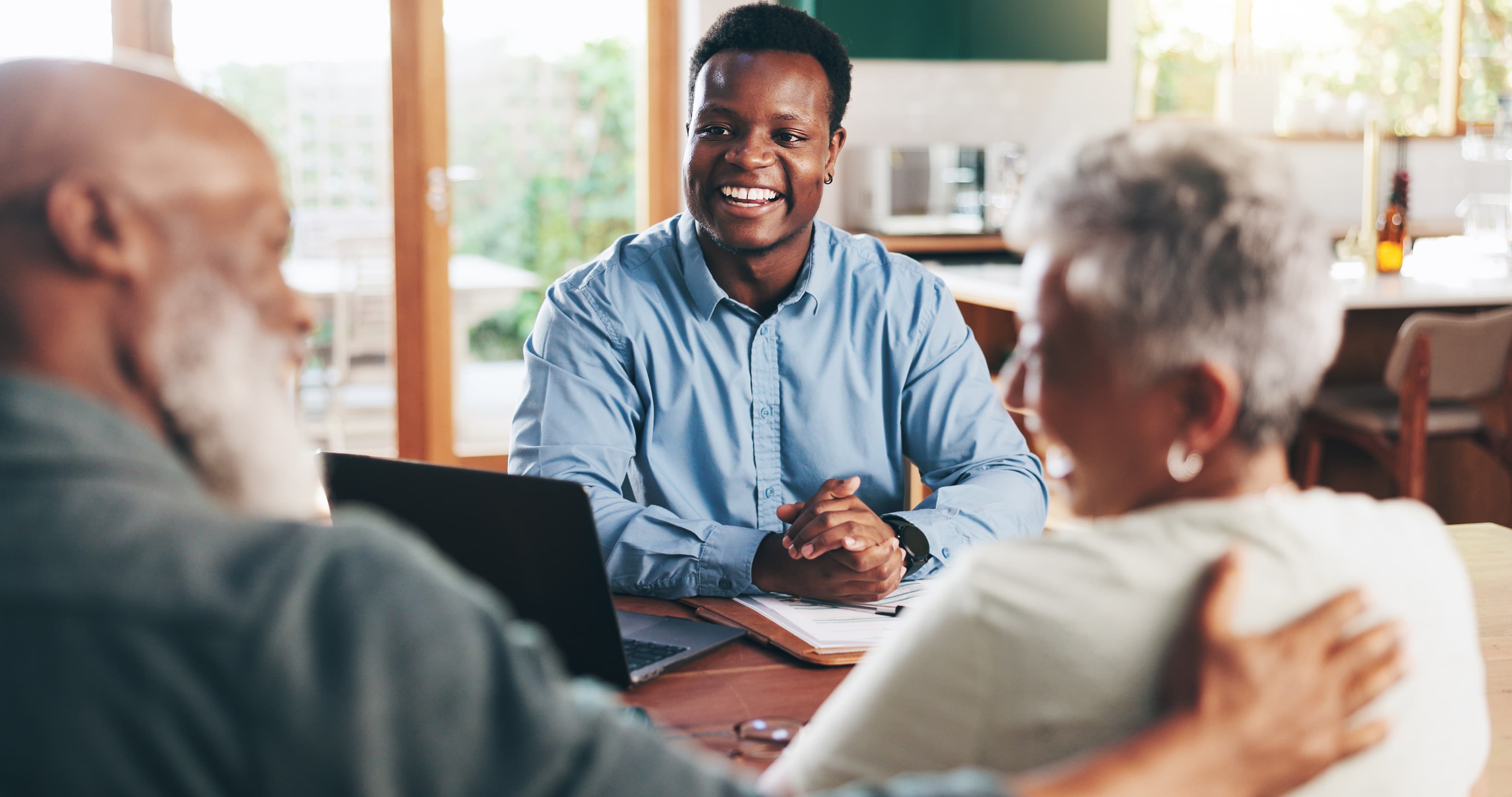 A man sitting at a table with two older women, engaged in conversation and sharing smiles.